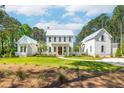 Beautiful two-story white home with a lush green lawn and a circular driveway nestled amongst mature trees at 821 Bulls Bay Blvd, Mount Pleasant, SC 29429