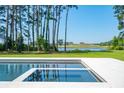 Modern zero-edge pool and spa overlooking a lush green golf course, a serene lake, and an elegant clubhouse at 821 Bulls Bay Blvd, Mount Pleasant, SC 29429