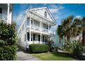 Two-story home with white trim, inviting double porches, and lush landscaping at 318 Sumter St, Charleston, SC 29403