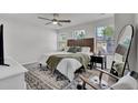 Bright bedroom with a large bed, a black nightstand, three windows, and an accent rug at 1032 Berry Patch Cir, Summerville, SC 29485