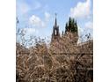 View of a historic church steeple with a golden cross against a cloudy sky at 106 Queen St # B, Charleston, SC 29401