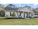 Charming home with a covered porch, black shutters, and a well-manicured lawn and landscaping at 218 Mohican Cir, Summerville, SC 29483