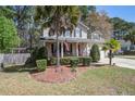 Well-manicured home with a front porch, a red door and nice landscaping with palm trees at 309 Edinburgh St, Summerville, SC 29483