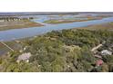 Aerial view of waterfront homes nestled amongst mature trees and surrounded by a beautiful marsh at 410 E Indian Ave, Folly Beach, SC 29439