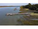 Scenic view of a weathered private dock along the marshy waterfront with boat and lush trees at 410 E Indian Ave, Folly Beach, SC 29439