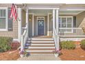 Inviting front porch with classic white columns and fresh flowers, enhancing the home's curb appeal at 4218 Club Course Dr, North Charleston, SC 29420