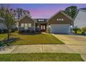 Charming home with a well-manicured lawn, a red front door and a two car garage at dusk at 718 Kilarney Rd, Summerville, SC 29483
