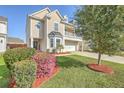 Inviting two-story home with a covered porch and beautifully landscaped front yard with flowers at 9988 Winged Elm St, Ladson, SC 29456