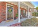 Cozy front porch with rocking chairs, a welcoming wreath, and classic brick columns at 103 Sago Palm Ct, Summerville, SC 29483