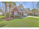 Beautiful two-story home featuring a lush green lawn, palm trees, and an inviting front porch at 103 Sago Palm Ct, Summerville, SC 29483