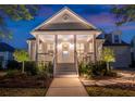 Inviting home exterior at twilight, showcasing a covered porch and manicured landscaping at 171 Cartright St, Charleston, SC 29492