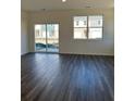 A naturally lit living room featuring gray wood floors, large windows, and sliding glass doors to outside at 1903 Scarlett Maple St, Summerville, SC 29486