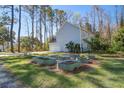 Side-view of backyard featuring garage, garden beds, and a tree-lined perimeter at 1926 Grimball Rd, Charleston, SC 29412