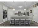 Well-lit kitchen with an island, stainless appliances, pendant lighting, tile backsplash, and gray wood flooring at 200 Bucksley Ln # 308, Charleston, SC 29492