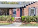 Close-up of a brick home's inviting pink front door framed by lush landscaping at 313 Runnymede Ln, Summerville, SC 29485