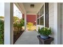 Inviting front porch featuring a concrete floor, stylish plant and a glimpse of the surrounding landscape at 467 Nelliefield Trl, Wando, SC 29492
