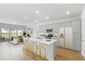 Open-concept kitchen featuring a central island with bar seating, modern appliances, and gray cabinets at 588 Red Monarch Way, Moncks Corner, SC 29461