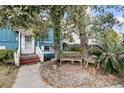 Inviting covered front porch with white railings and a bench, surrounded by lush greenery at 702 E Erie Ave, Folly Beach, SC 29439
