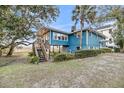 Backyard view of a charming blue two-story home with a wooden deck overlooking the beautiful marsh at 702 E Erie Ave, Folly Beach, SC 29439