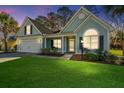 Charming home boasts a well-manicured lawn, attached garage, and lovely curb appeal at twilight at 8502 Sentry Cir, North Charleston, SC 29420