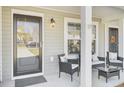Inviting front porch with seating area, featuring a stylish door and well-placed lighting at 9712 Transplanter Cir, Ladson, SC 29456