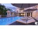 Relaxing poolside with multiple lounge chairs and umbrellas with a partial view of the home at 1077 Ship Builder St, Charleston, SC 29492