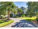 Elegant home with lush landscaping, a circular driveway, and palm trees at 1302 Middle St, Sullivans Island, SC 29482