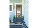 Stylish front door with glass pane, flanked by planters and a lantern style sconce at 2545 Hatch Dr, Johns Island, SC 29455