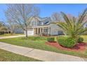 Inviting tan home with a well-kept lawn, palm trees, and a two-car garage with a concrete driveway at 4979 Ballantine Dr, Summerville, SC 29485
