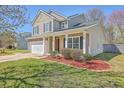 Attractive tan two-story home featuring a manicured lawn, a two-car garage, and a covered front porch at 4979 Ballantine Dr, Summerville, SC 29485