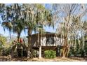 Charming elevated exterior featuring wooden deck, stairs and mature trees at 12 Dune Crest Trace Trl, Johns Island, SC 29455