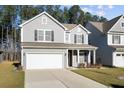 Charming two-story home with gray siding, well-manicured lawn, and a two car attached garage at 128 Surfbird Rd, Summerville, SC 29486