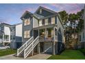 Charming two-story home features a welcoming porch and manicured front yard at dusk at 312 Coki Amalie Ct, Charleston, SC 29492