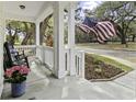 Inviting front porch with rocking chairs, complemented by lush greenery and a charming American flag at 5108 Celtic Dr, North Charleston, SC 29405