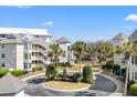 View of the complex, with palm trees lining the circular driveway, showing the building's layout and landscaping at 9000 Palmetto Dr # G203, Isle of Palms, SC 29451