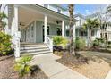 Inviting front porch with white columns, ceiling fans, and a glimpse of the neighboring homes in the community at 1429 Lettered Olive Ln, Mount Pleasant, SC 29464