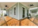 Expansive front porch with rich wood flooring, ceiling fans, and comfortable seating for relaxing outdoors at 1429 Lettered Olive Ln, Mount Pleasant, SC 29464