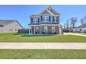 Charming two-story home with a lush green lawn, blue siding, and stone accents, creating curb appeal at 175 Darby Meadow Ln, Ridgeville, SC 29472