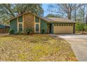 Inviting home with green siding, stone details, a well-kept lawn, and an attached garage at 2306 Chairmaker Ct, Charleston, SC 29414