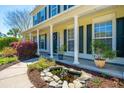 Inviting front porch with decorative landscaping, a charming pond, and white pillars with dark shutters at 9408 Harroway Rd, Summerville, SC 29485