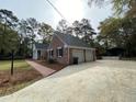 Spacious two-car garage with brick exterior, paved driveway, and lush landscaping, creating curb appeal at 116 W Johnston St, Summerville, SC 29483