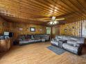 Living room featuring wood-paneled walls, a ceiling fan, comfortable seating, and laminate wood flooring at 1393 Russellville Rd, Saint Stephen, SC 29479