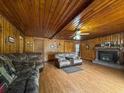 Cozy living room with wood-paneled walls and a brick fireplace, showcasing comfortable seating and a ceiling fan at 1393 Russellville Rd, Saint Stephen, SC 29479