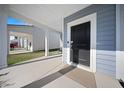A welcoming front porch featuring a black front door, concrete flooring, and a view of a well-maintained yard at 173 Paddle Boat Way, Summerville, SC 29485