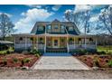 Inviting two-story home boasts a spacious wraparound porch, enhanced by lush landscaping and a concrete driveway at 212 Chester Ln, Cottageville, SC 29435