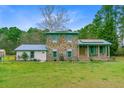 Charming two-story brick home with blue shutters, a metal roof, solar panels, and a well-manicured lawn at 276 S Railroad Ave, Harleyville, SC 29448