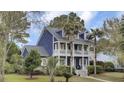 Two-story home with double porches framed by palm trees and green lawn at 3409 Southern Cottage Way, Mount Pleasant, SC 29466