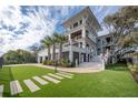 Well-manicured front yard with lush grass, palm trees, brick-paved walkway, and multi-story home at 3803 Palm Blvd, Isle of Palms, SC 29451