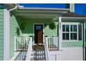 Inviting front porch with fern planters, outdoor seating, and a dark wood front door at 4281 Jacobs Point Ct, Ravenel, SC 29470