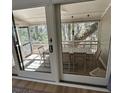 View through sliding glass doors to screened porch with wicker chairs and dining table and tree backdrop at 60 Fairway Dunes Ln, Isle of Palms, SC 29451